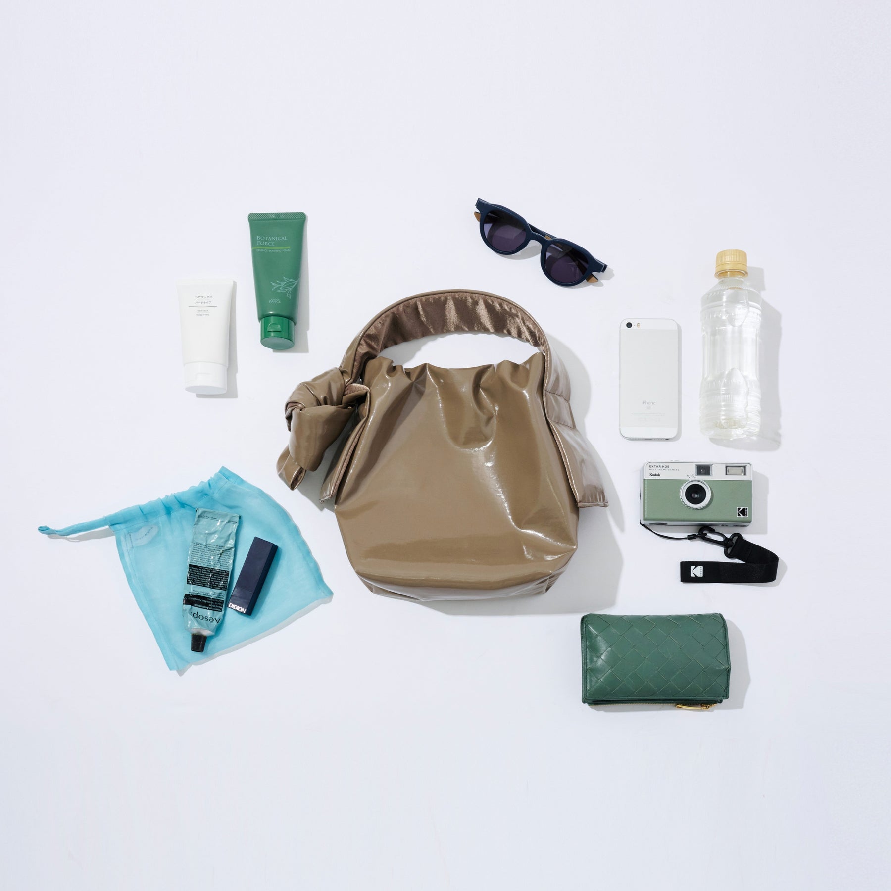 Collection of travel items including a beige bag, sunglasses, water bottle, and toiletries on a white background