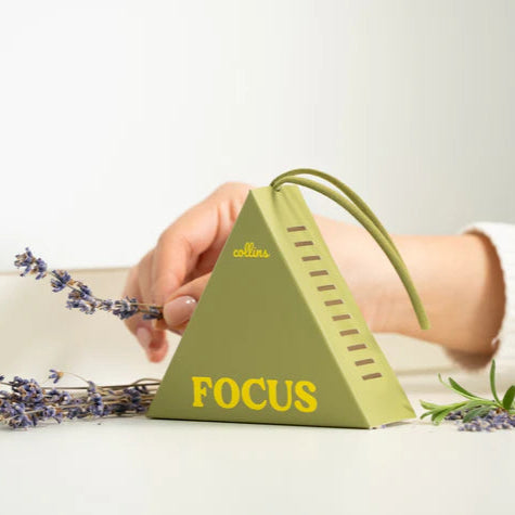 Green pyramid-shaped fragrance sachet labeled 'FOCUS' with lavender flowers on a light background