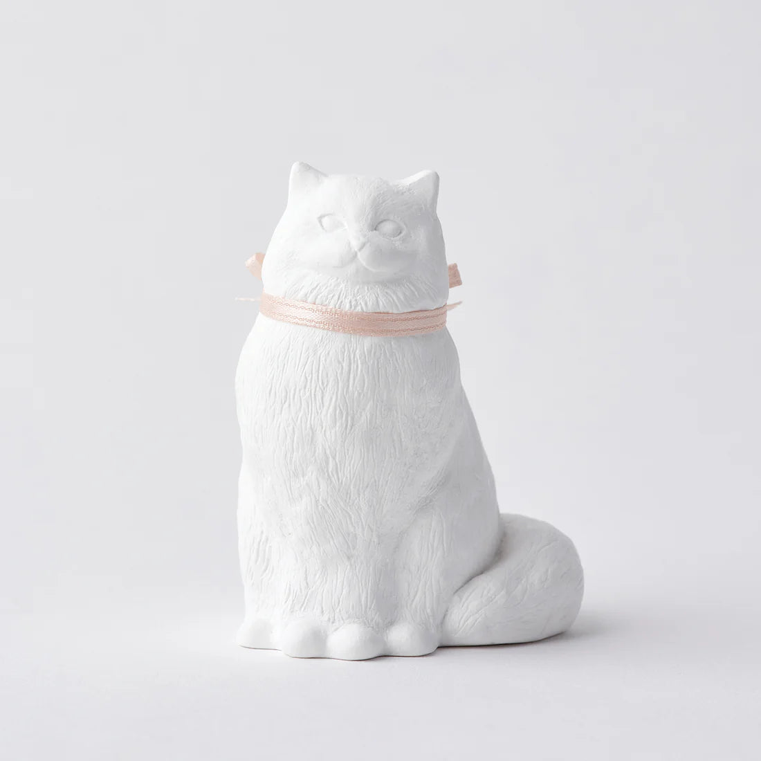 White ceramic cat-shaped object on a light gray background