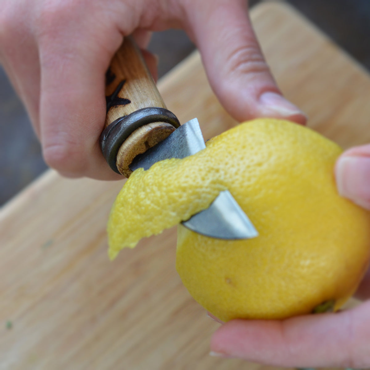 Master Shin's Anvil, #58 rustic Paring Knife, small with concave blade - lifestyle photo of knife peeling lemon 