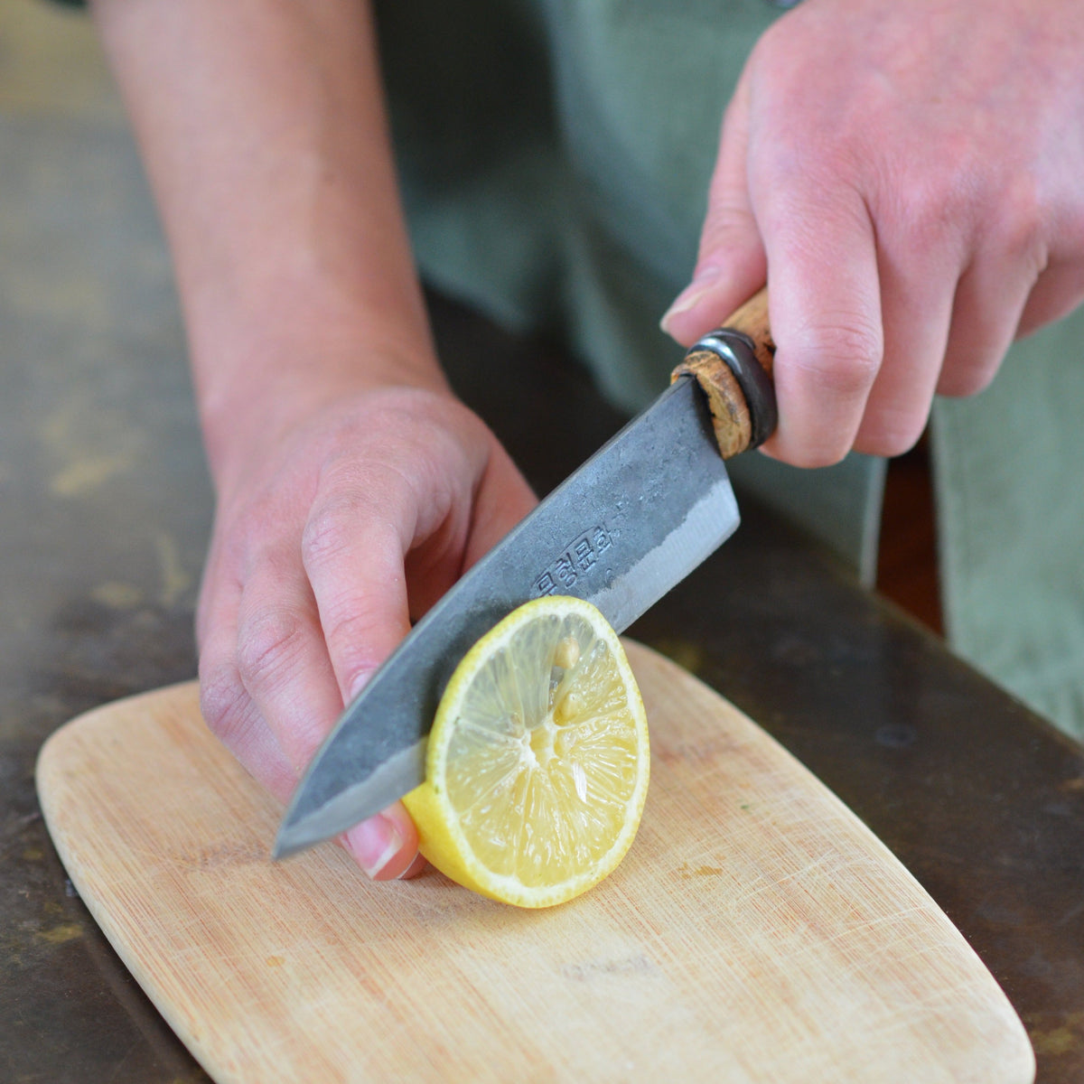 Master Shin's Anvil, #61 Sashimi Knife, lifestyle photo of man slicing lemon