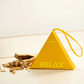 Yellow triangular fragrance sachet labeled 'RELAX' with a small amount of gold-like material on a white surface.