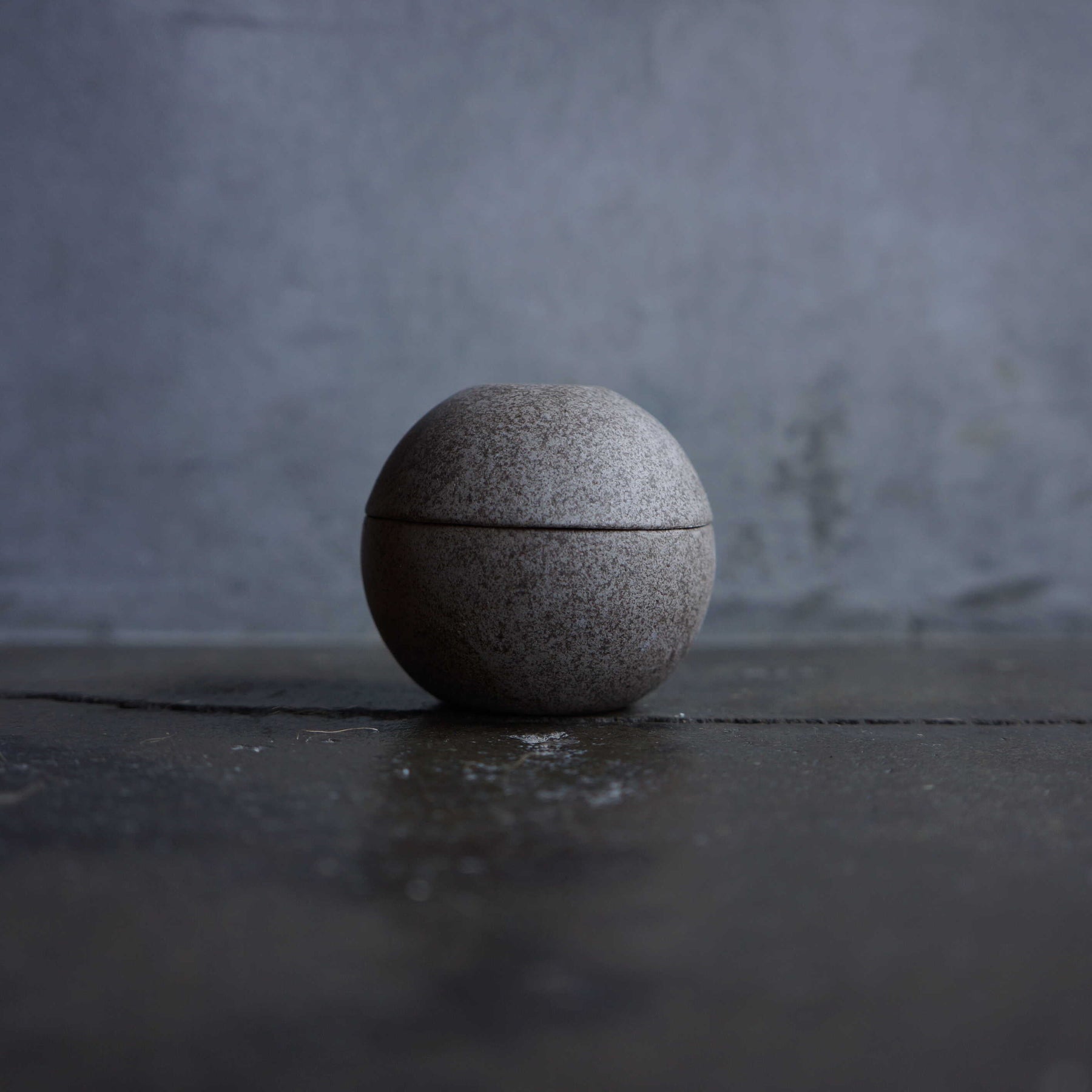 Round stone-like object on a dark surface with a gray background