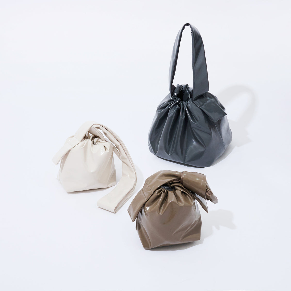 Three fabric bags in beige, gray, and brown on a white background