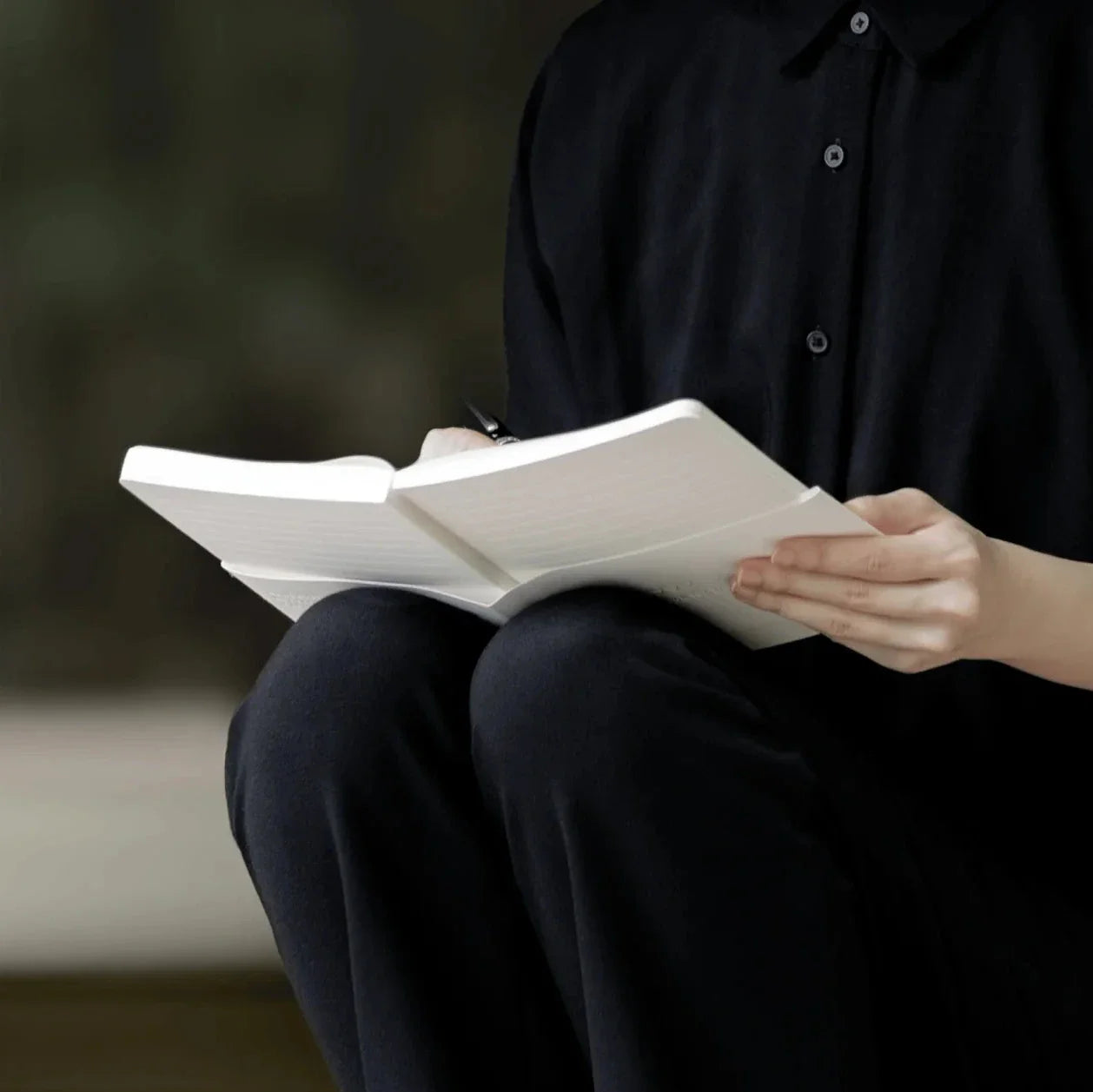 Person sitting and reading a book with a blurred background