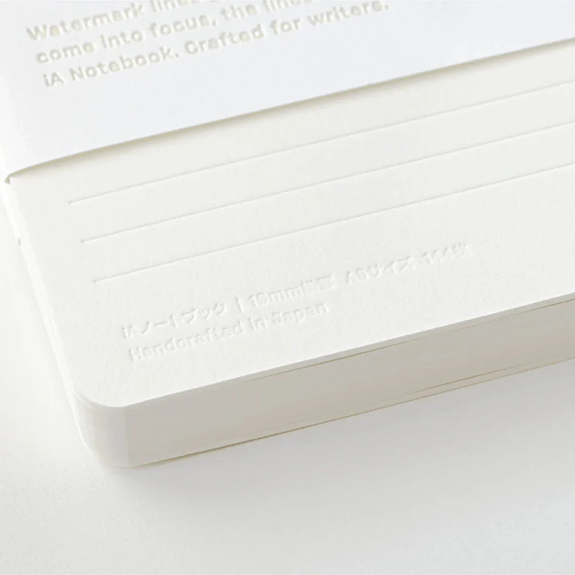 White notebook with embossed text on a light gray background