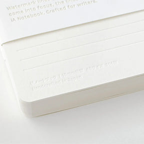 White notebook with embossed text on a light gray background