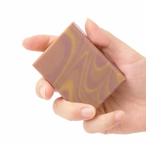 Hand holding a marbled soap bar with a white background