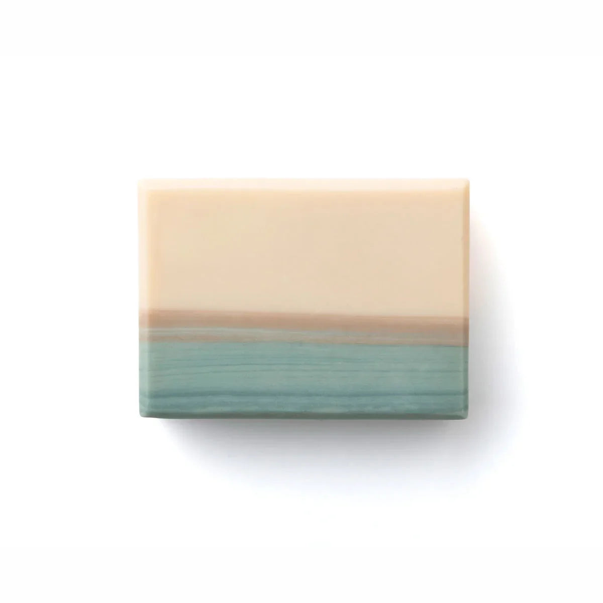 A rectangular bar of soap with a two-tone design, featuring a warm cream-colored top half and a textured teal-green bottom half with a thin tan band in the middle, shown on a plain white background.