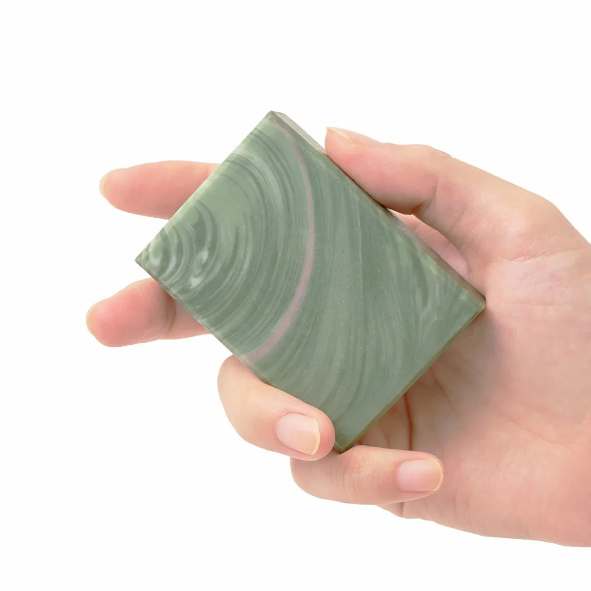 Hand holding a green marbled soap bar against a white background